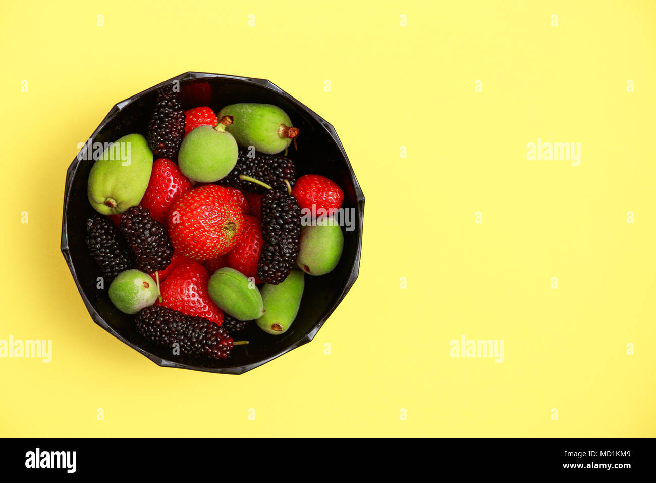 Délicieux avec les fruits d'été sur un fond jaune frais mise à plat. Cerise, mûre, fraise dans une assiette de service. Haut de la vue plate Banque D'Images