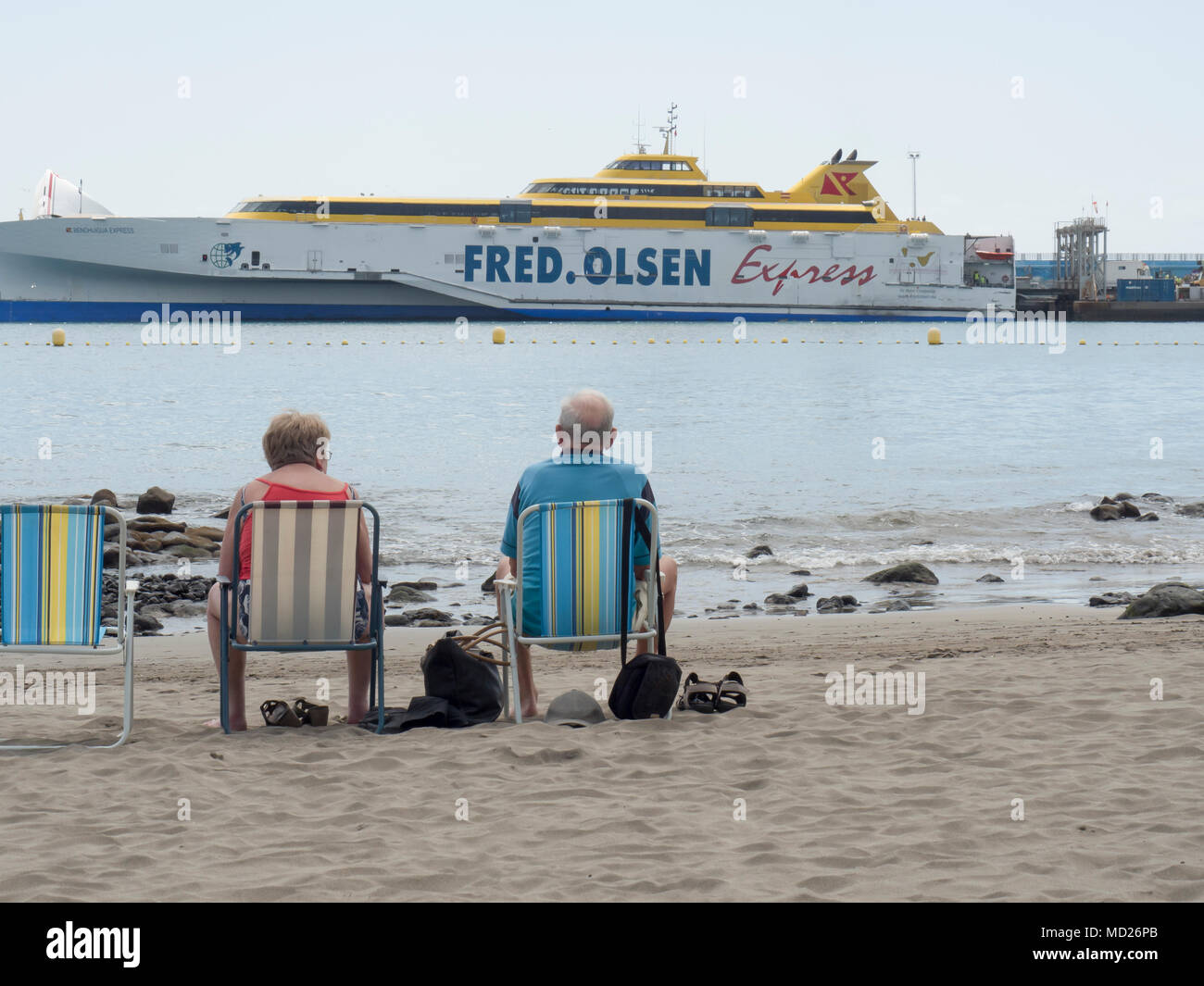 Couple de personnes âgées assis dans des transats sur la plage face à la mer à la Fred Olsen cruise ship Santa Cruz de Tenerife, Espagne Banque D'Images