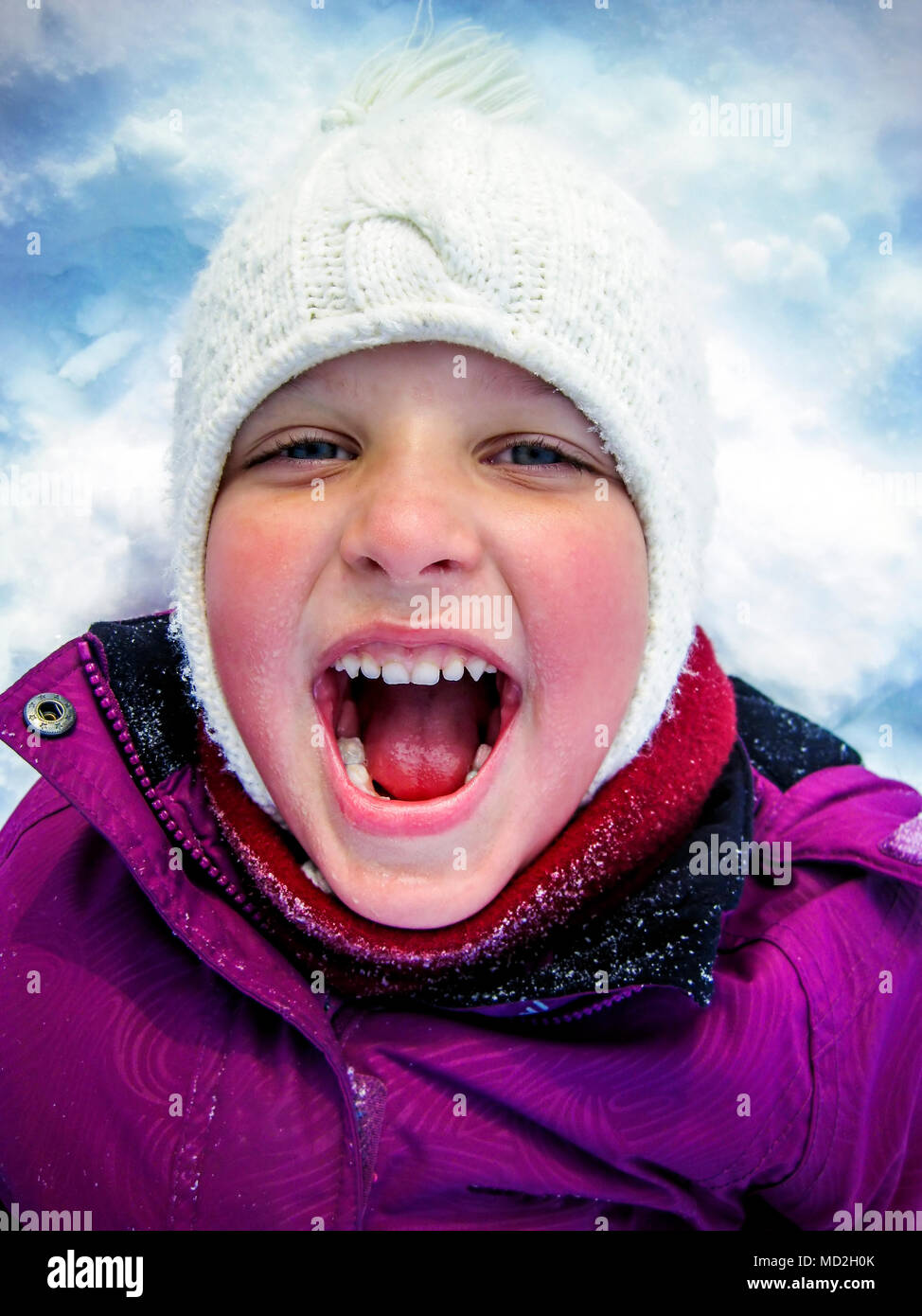 Petite fille pose dans la neige avec la bouche ouverte. Banque D'Images