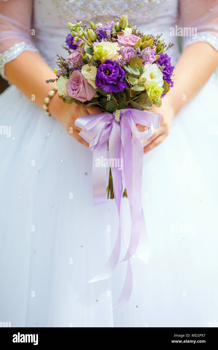 Mariée en robe blanche holding purple bouquet de mariage en mains, libre. Concept de mariage Banque D'Images Mariée en robe blanche holding purple bouquet de mariage en mains, libre. Concept de mariage Banque D'Images