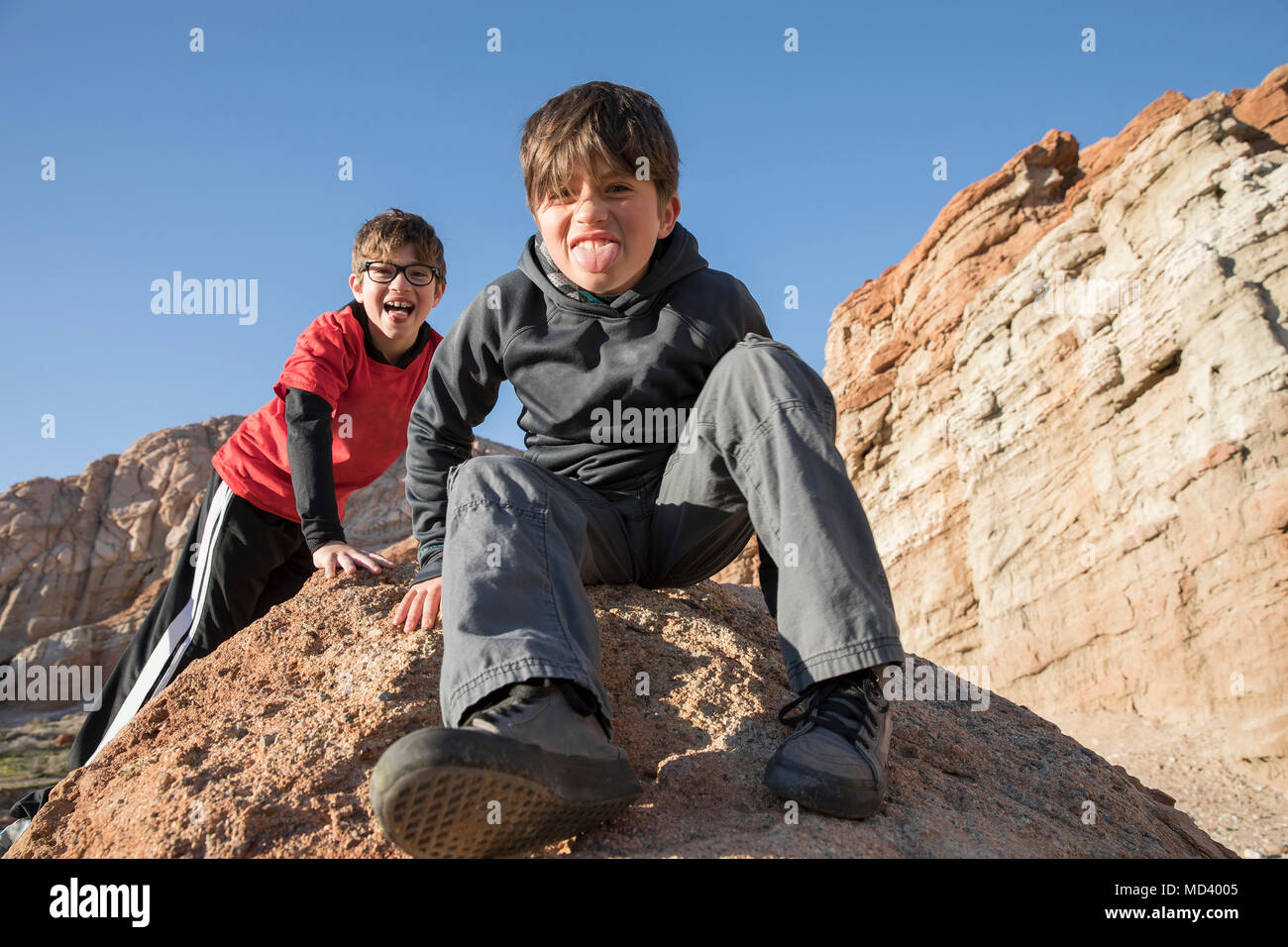 Portrait de garçons assis sur le roc, sticking out tongue, Lone Pine, Californie, USA Banque D'Images