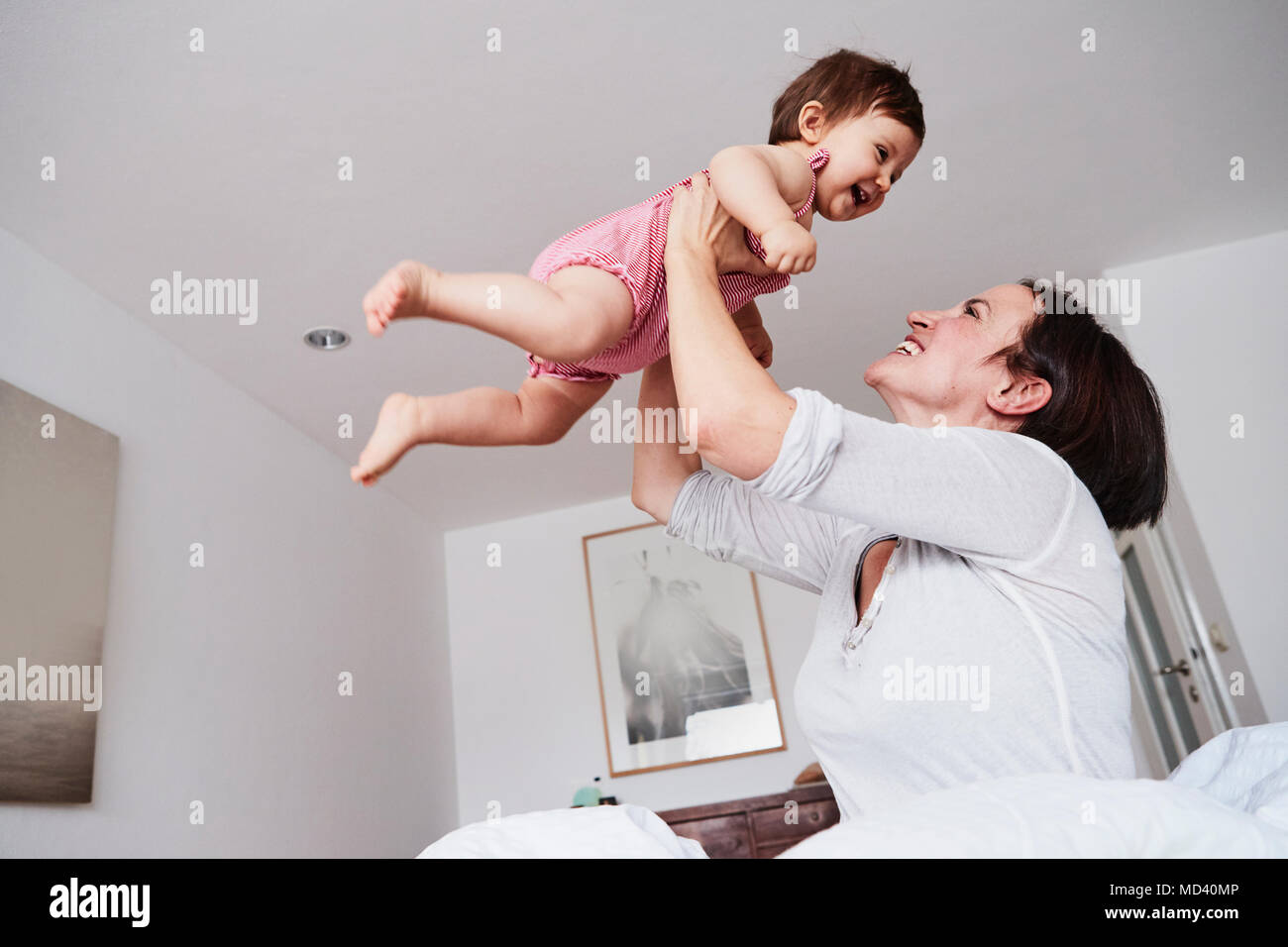 Mère tenant sa petite fille à l'air, low angle view Banque D'Images