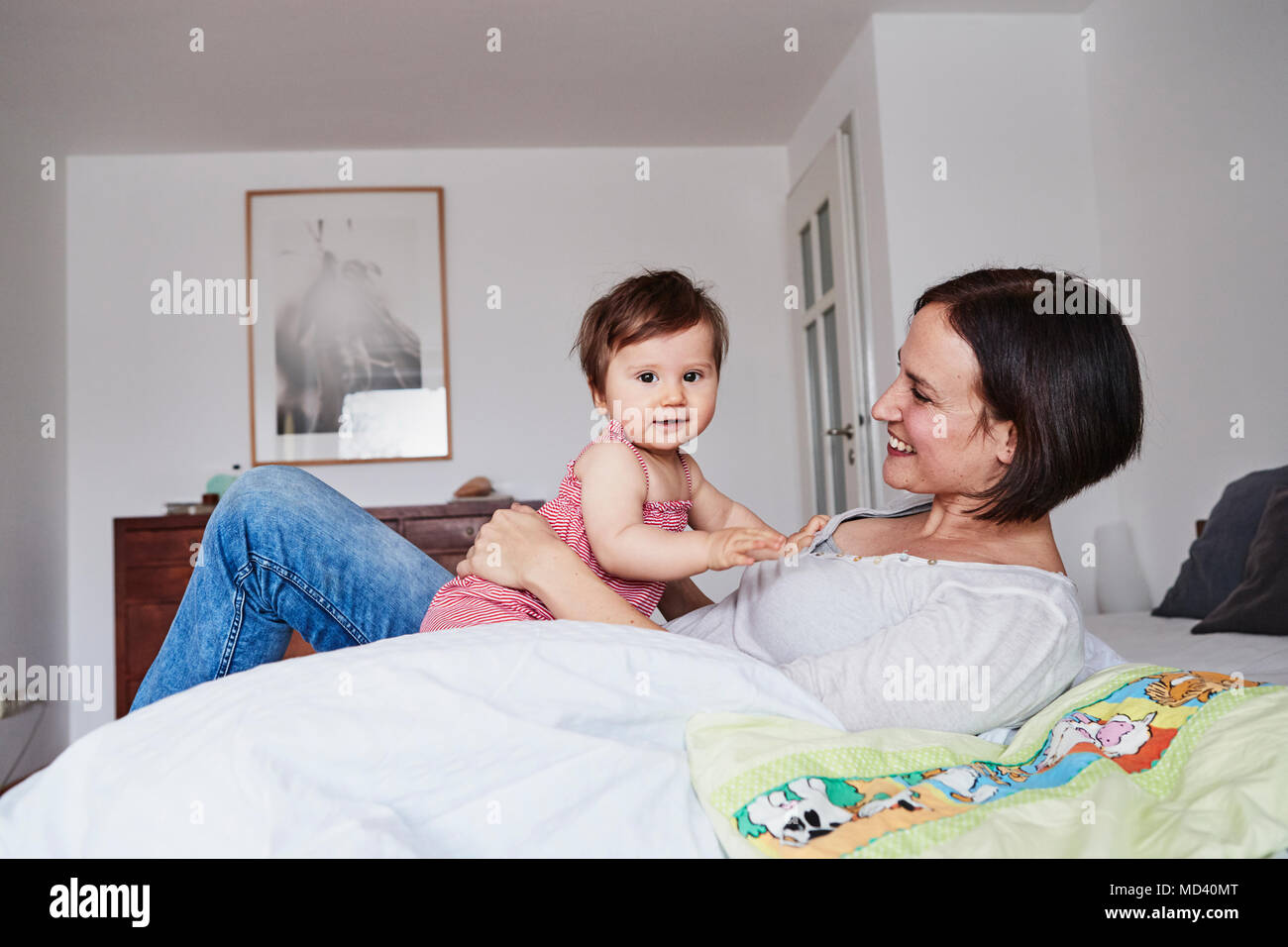 Mère et fille de bébé détente sur lit Banque D'Images