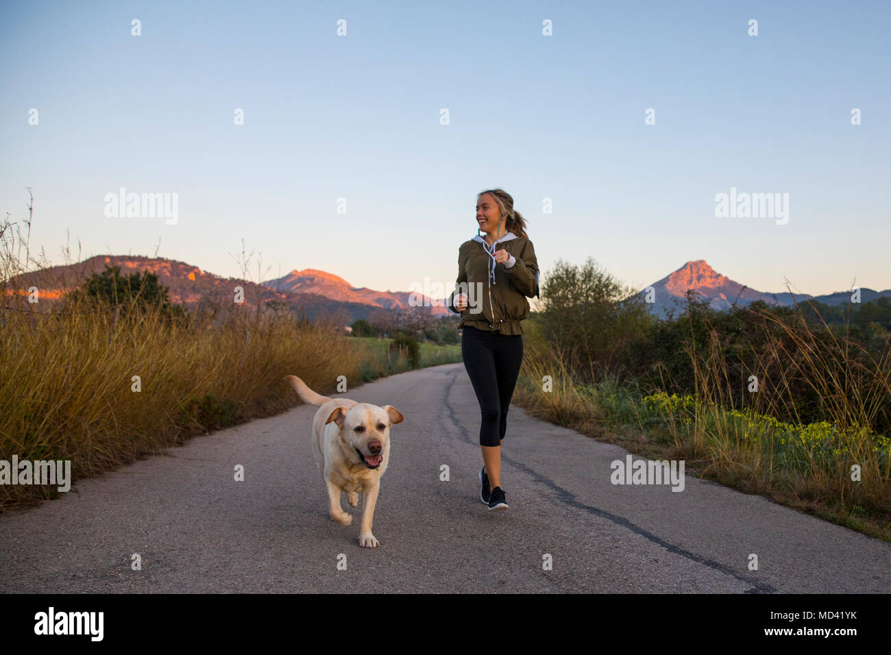 Jeune femme tournant le long chemin rural avec chien Banque D'Images