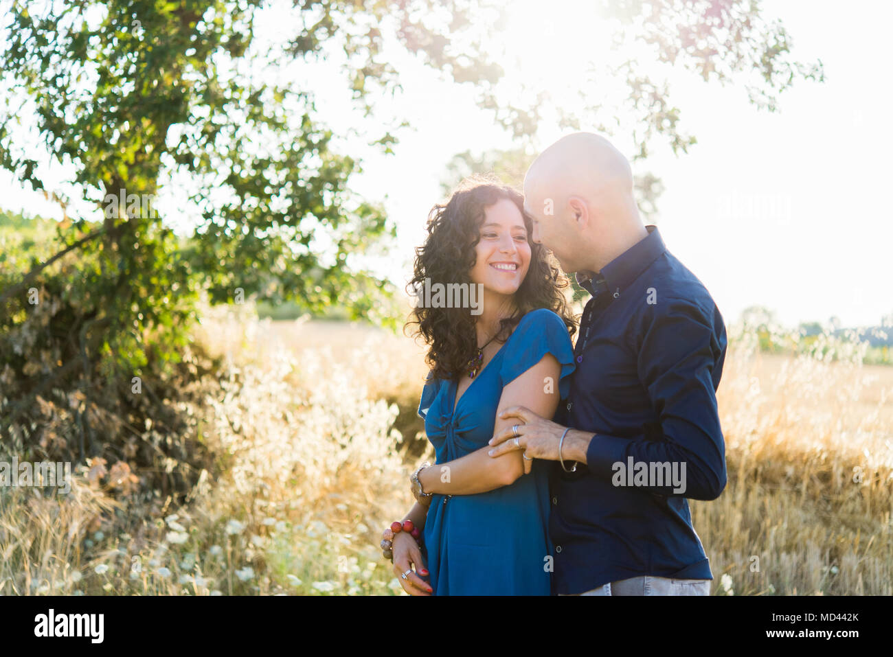 Couple standing in field, hugging Banque D'Images