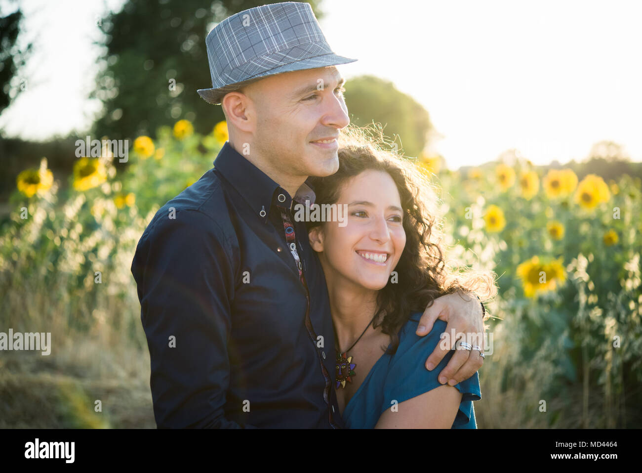 Couple standing in champ de tournesols, hugging Banque D'Images