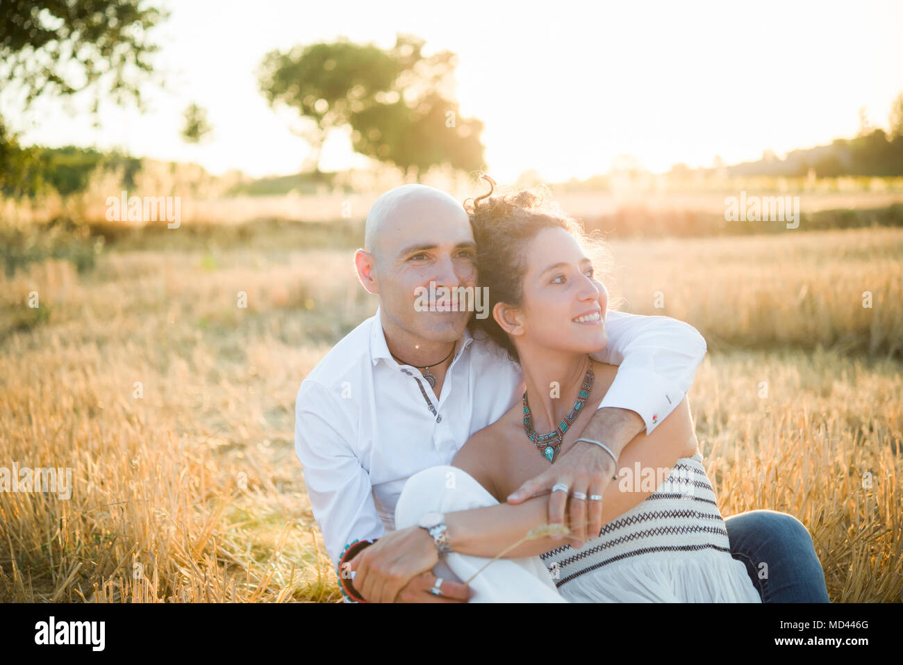 Couple sitting in field, hugging Banque D'Images