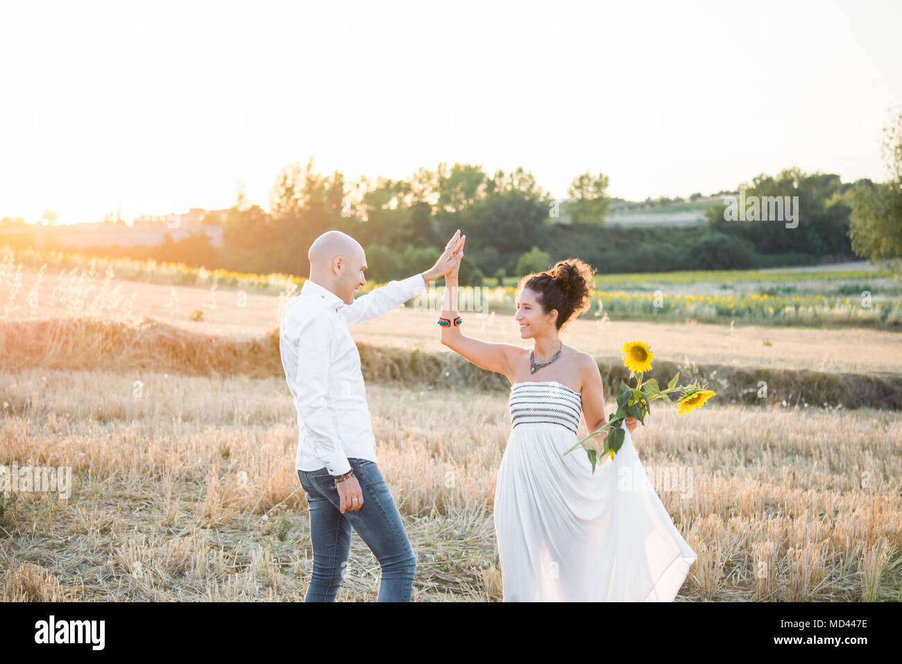 Couple hétérosexuel danser dans les champs, woman holding sunflowers in hand Banque D'Images