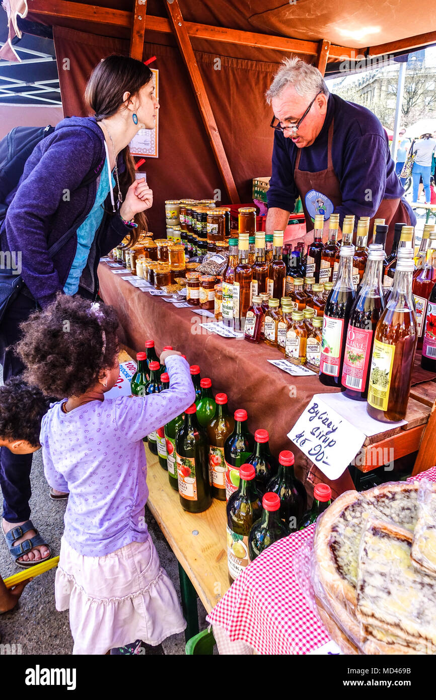 Jeune femme avec enfant choisissant des marchandises, marché de l'agriculteur stand avec spiritueux, liqueurs à la place Kulatak, Dejvice Prague, République tchèque Europe Banque D'Images
