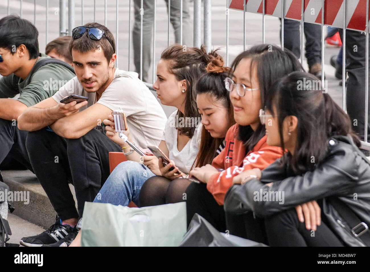 Milan, Italie 04 mars 2018 : les jeunes gens assis dans la place de la ville communiquent à l'aide de leur smartphone. Banque D'Images