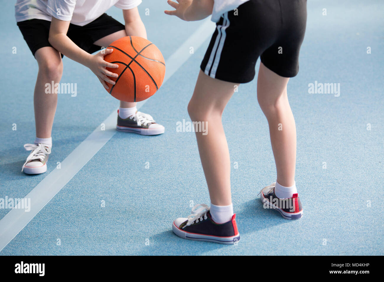 Photo recadrée d'élèves jouant au basket-ball dans la salle de sport Banque D'Images