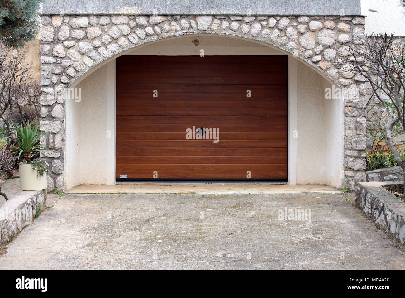 Rouleau moderne porte de garage en métal avec finition grain imitation bois  à l'intérieur du cadre traditionnel mur de pierre Photo Stock - Alamy