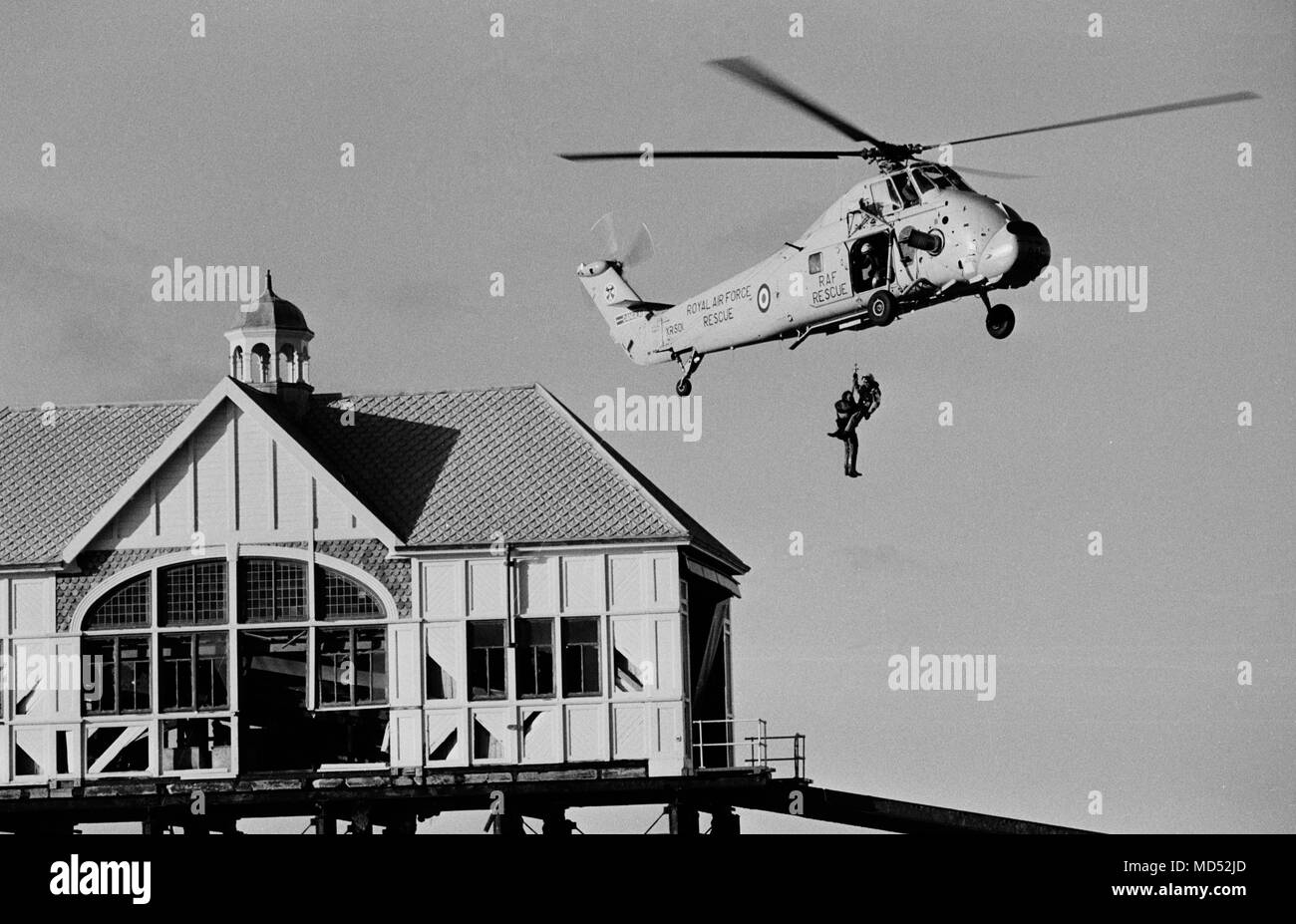 Deux des sept hommes d'équipage de sauvetage de descendre d'un hélicoptère de sauvetage de la Royal Air Force à leur station battues à Margate Pier, qui a été laissé isolé dans la mer après les orages violents. Banque D'Images