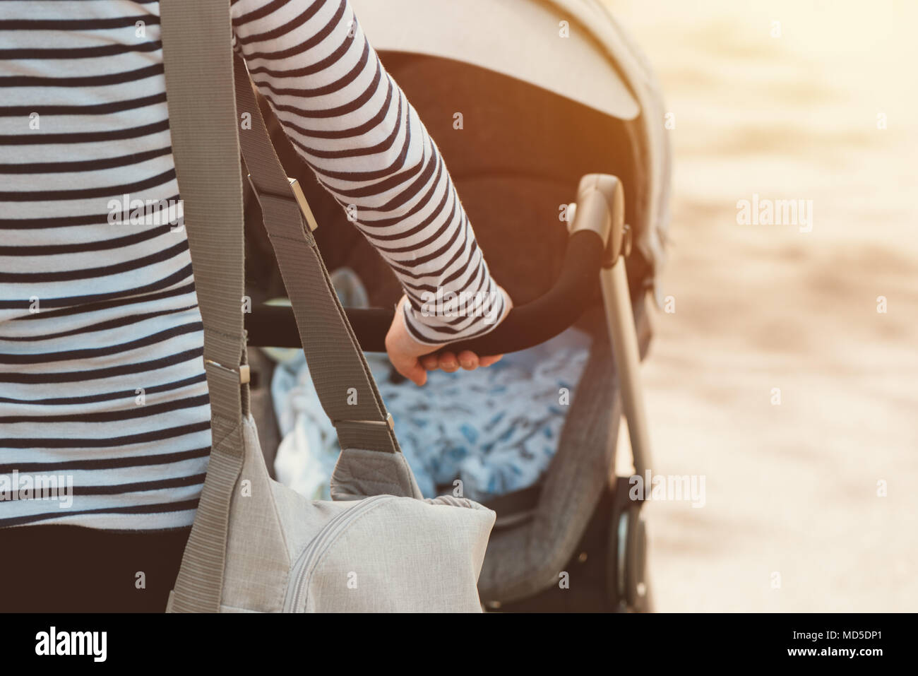 Mère marcher avec bébé dans une poussette sur journée de printemps ensoleillée Banque D'Images