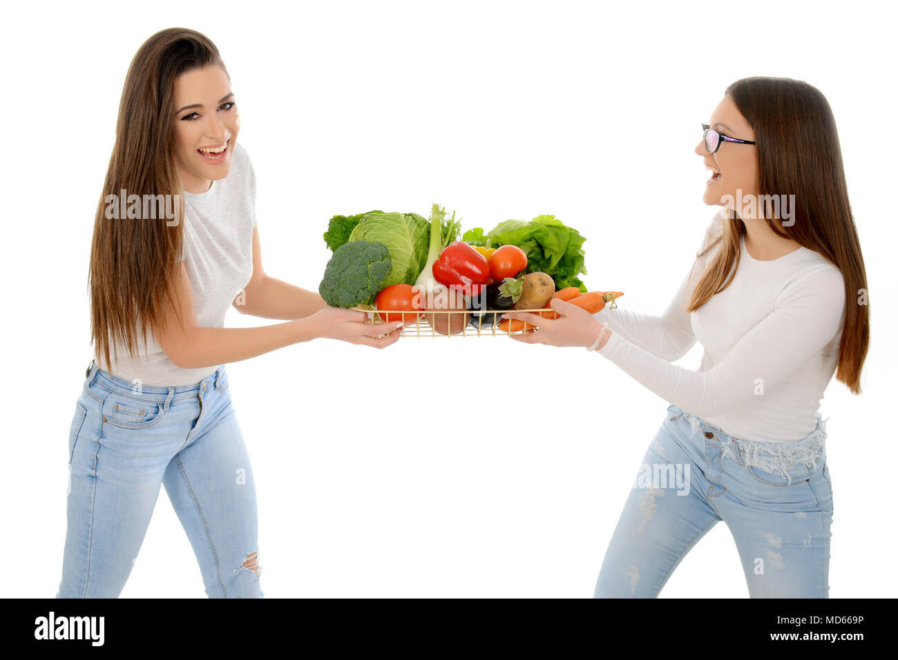 Deux filles rire ruée pour panier plein de légumes Banque D'Images