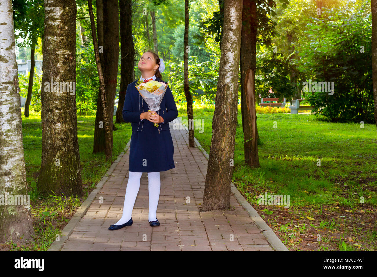 Peu d'abord élève, étudiant fille va à l'école sur le savoir jour 1. Septembre. Élève de l'école élémentaire en uniforme avec des fleurs en automne Banque D'Images