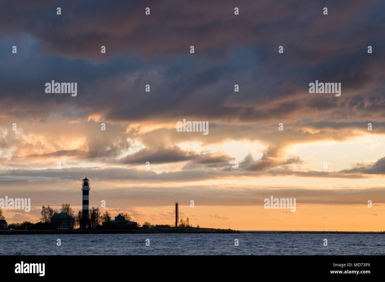 Beaux nuages dans la lumière chaude d'un soleil couchant sur un phare sur une station. Banque D'Images