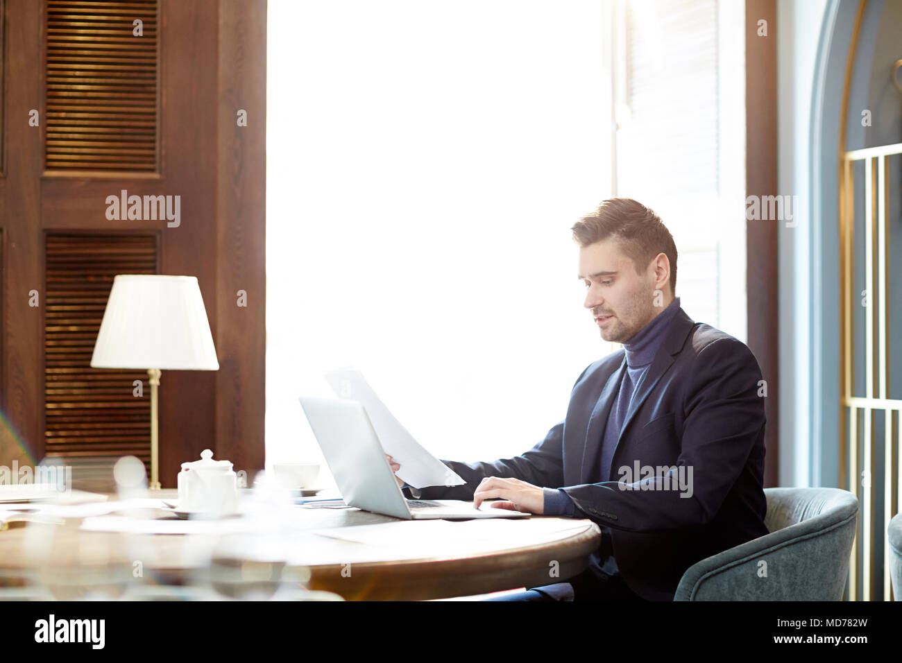 D'âge moyen concentré Caucasian businessman working on laptop et à l'intermédiaire de documents de bureau moderne Banque D'Images
