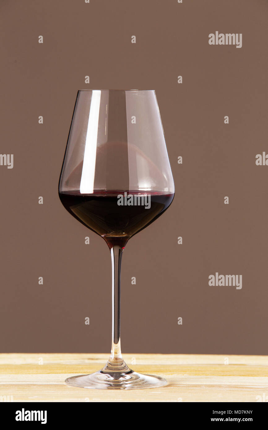 Un verre de vin rouge sur la table en bois sur fond brun. Banque D'Images