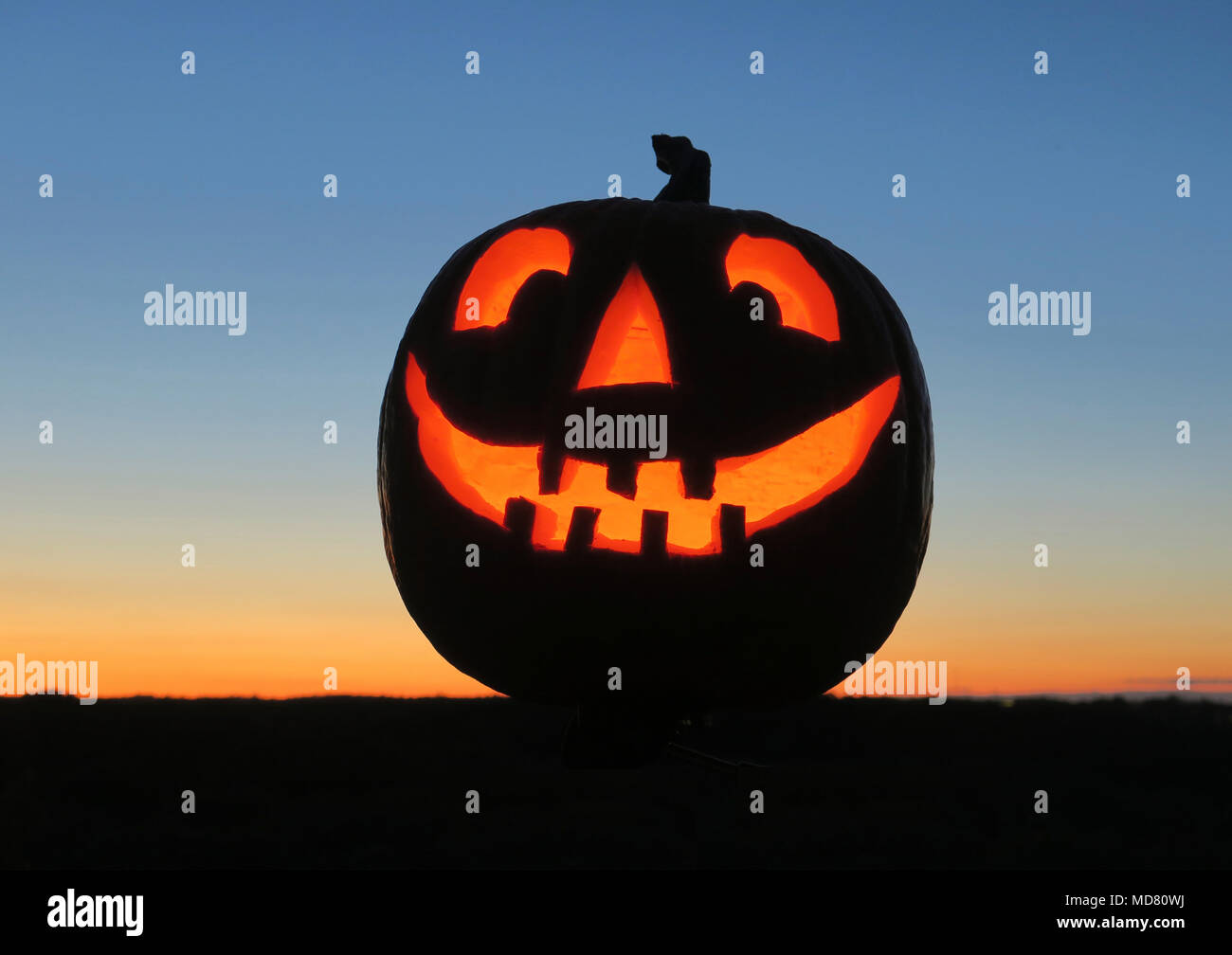 La vie encore d'une citrouille sculptée rougeoyante ou Jack O' Lantern éclairée de l'intérieur contre un arrière-plan du crépuscule Banque D'Images