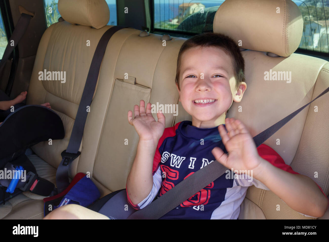 Portrait of happy little boy dans la ceinture de sécurité de voiture Banque D'Images