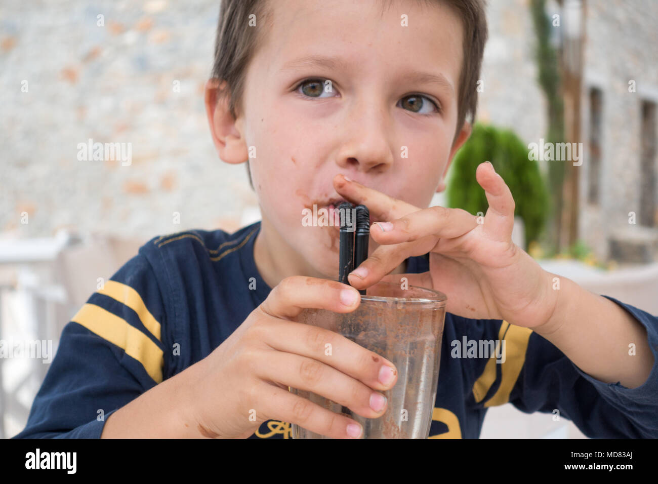 Cute little boy drinking milk-shake au chocolat au restaurant Banque D'Images