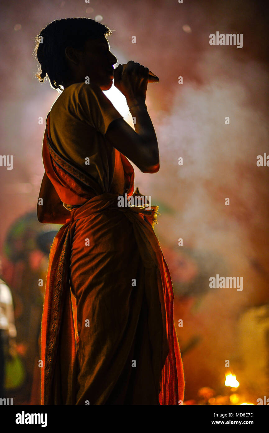 L'hindouisme : un jeune prêtre souffle une conque pendant la Ganga Aarti puja (cérémonie du soir) à Varanasi, Inde Banque D'Images