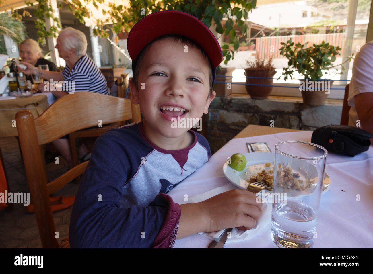 Portrait of happy little boy having meal at restaurant Banque D'Images