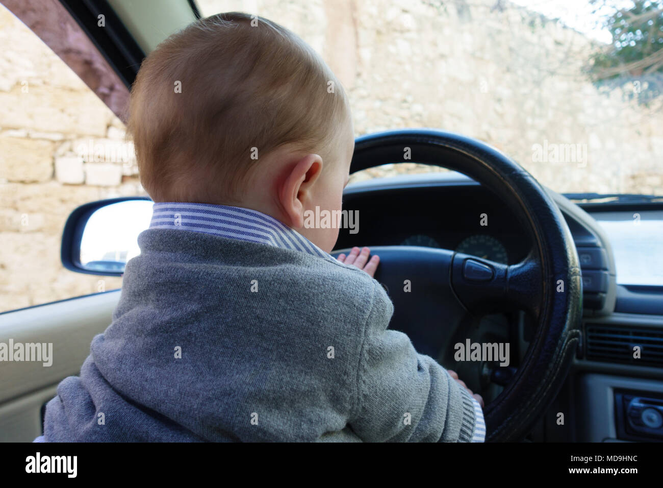 Adorable bébé garçon derrière le volant de voiture Banque D'Images