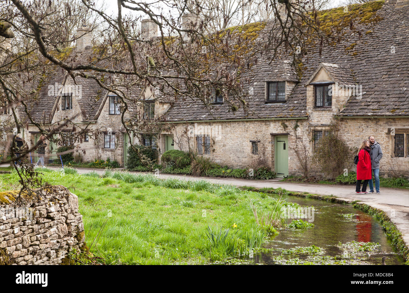 L'homme et la femme se placer à côté de la rivière Colne extérieur Arlington row dans le village de Cotswold Anglais Bibury Gloucestershire administré par le National Trust Banque D'Images