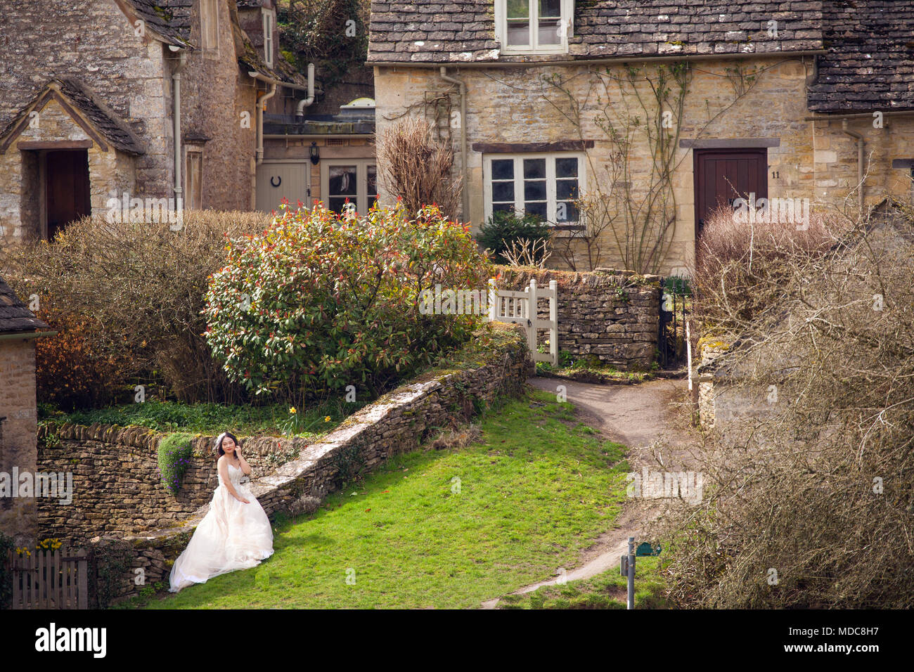 La mariée asiatique pose pour la photographie de mariage dans le village anglais Cotswold de Bibury Gloucestershire Banque D'Images