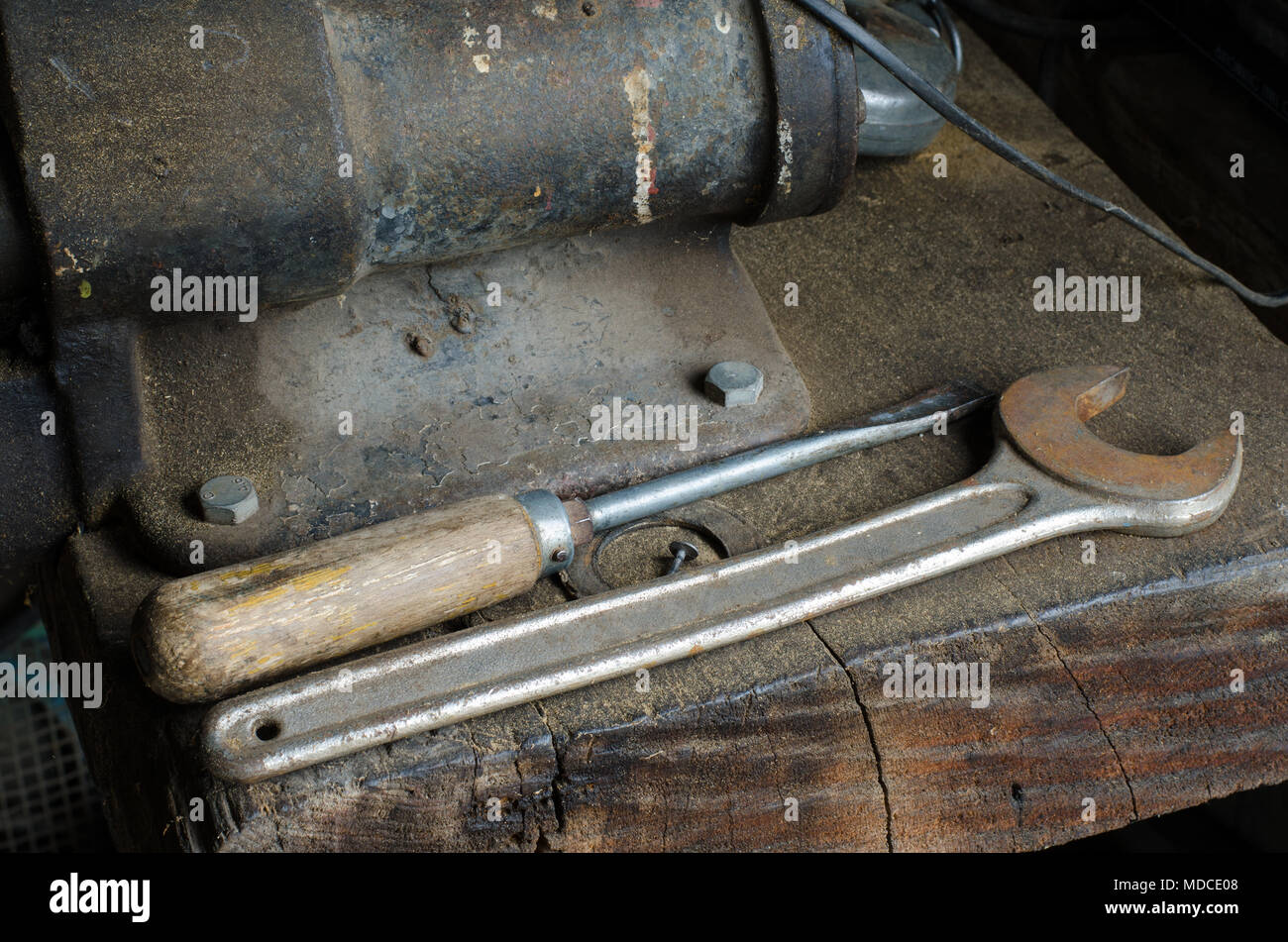 Vieux métal tournevis à cliquet et allongé sur une table de travail en bois poussiéreux Banque D'Images