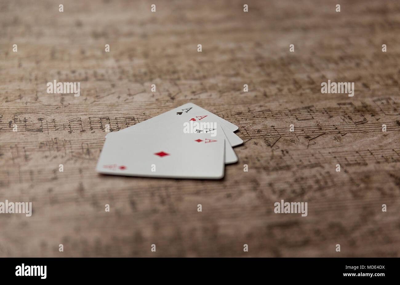 Carte à jouer quatre as empilés sur une vieille feuille de musique. Banque D'Images