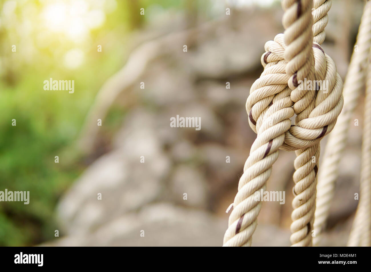 Close-up of rope knot line attachés ensemble avec un arrière-plan de pont. Corde blanche dans un noeud pour l'aventure.Corde, attachez un noeud lié à un maillage de poteau de métal Banque D'Images