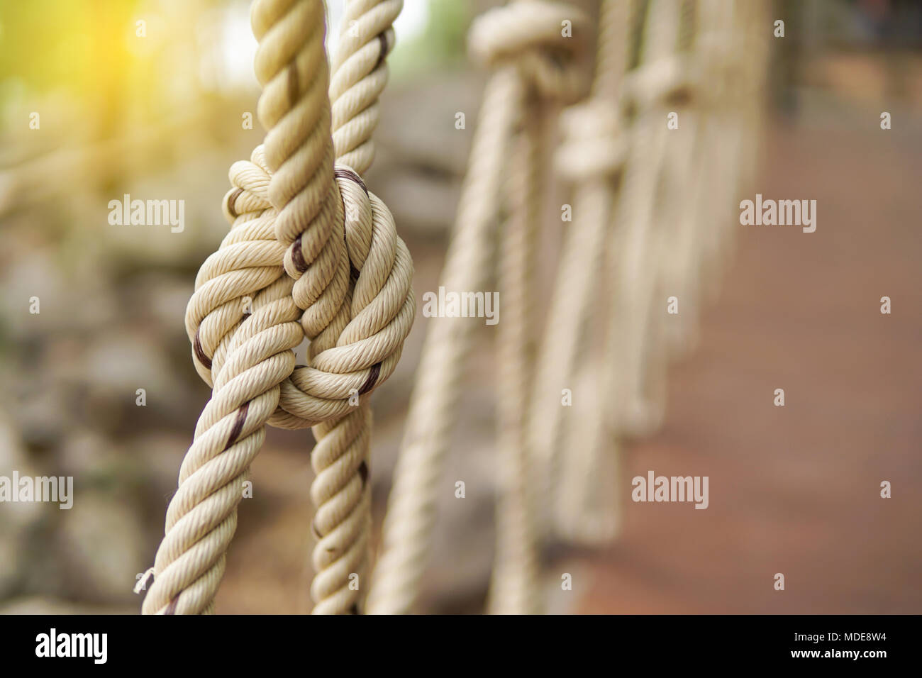 Close-up of rope knot line attachés ensemble avec un arrière-plan de pont. Corde blanche dans un noeud pour l'aventure.Corde, attachez un noeud lié à un maillage de poteau de métal Banque D'Images