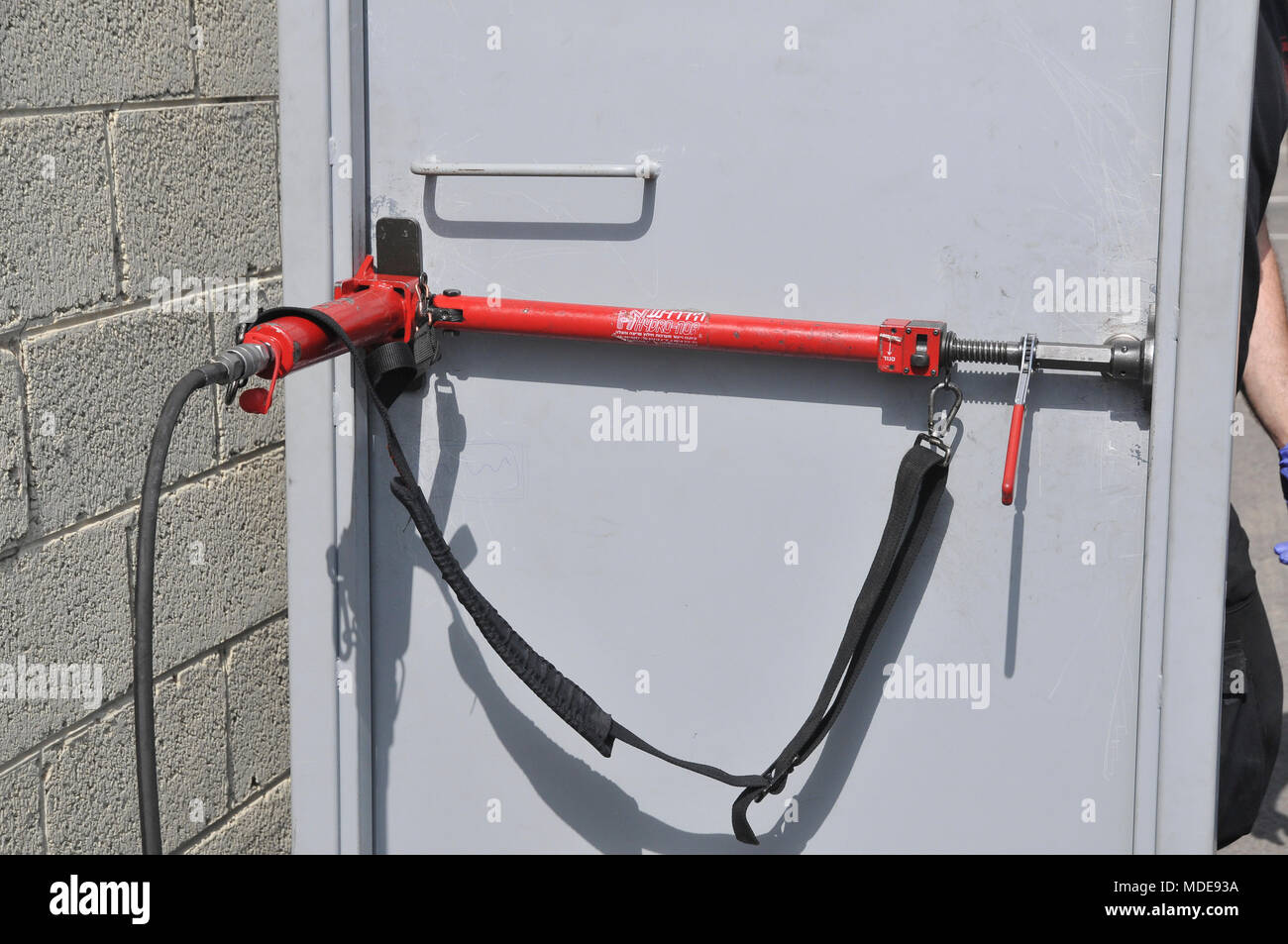 Fire fighter utilise les outils hydrauliques à enfreindre une porte verrouillée Banque D'Images