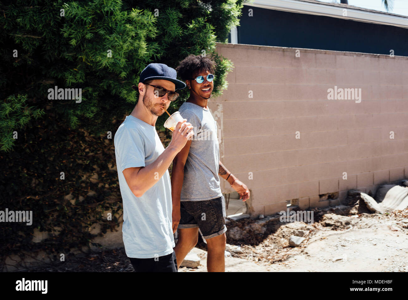 Les amis marchant sur un chemin de terre par wall Banque D'Images