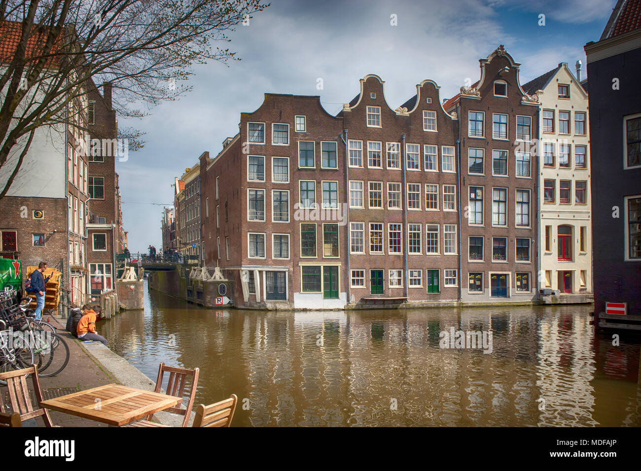 Amsterdam, Pays-Bas - 14 avril 2018 vieux bâtiments typiques d'Amsterdam, le long du canal. Les gens sur les bancs. Tulipes en bains à remous Banque D'Images