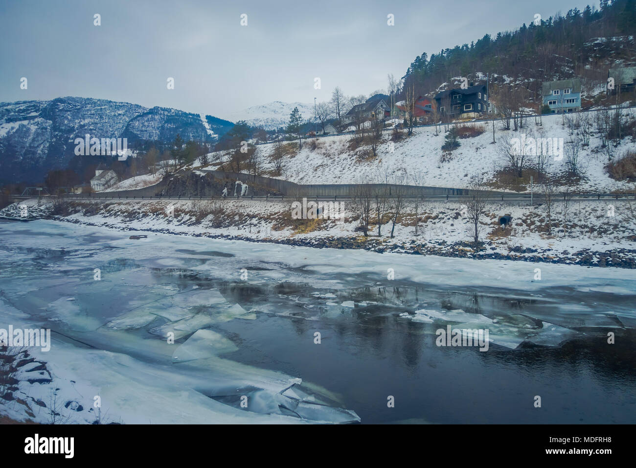Vue extérieure de rivière gelée avec quelques maisons en bois sur un côté de la route à la montagne du GED sont Banque D'Images