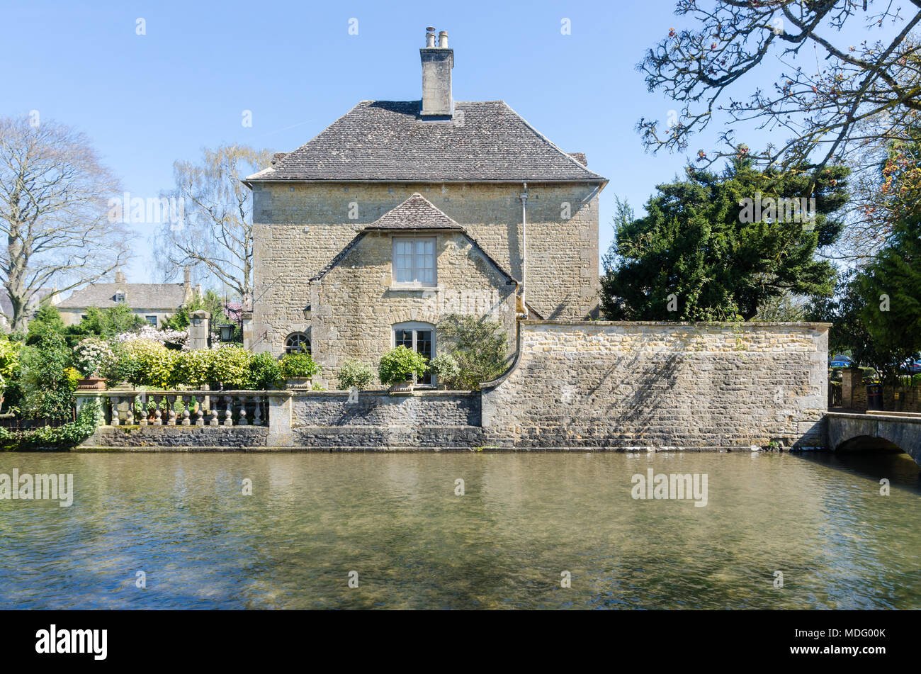 Jolie maison en pierre de Cotswold à côté de la rivière Windrush dans le populaire village de Cotswold Bourton-on-the-water, Gloucestershire dans soleil du printemps Banque D'Images