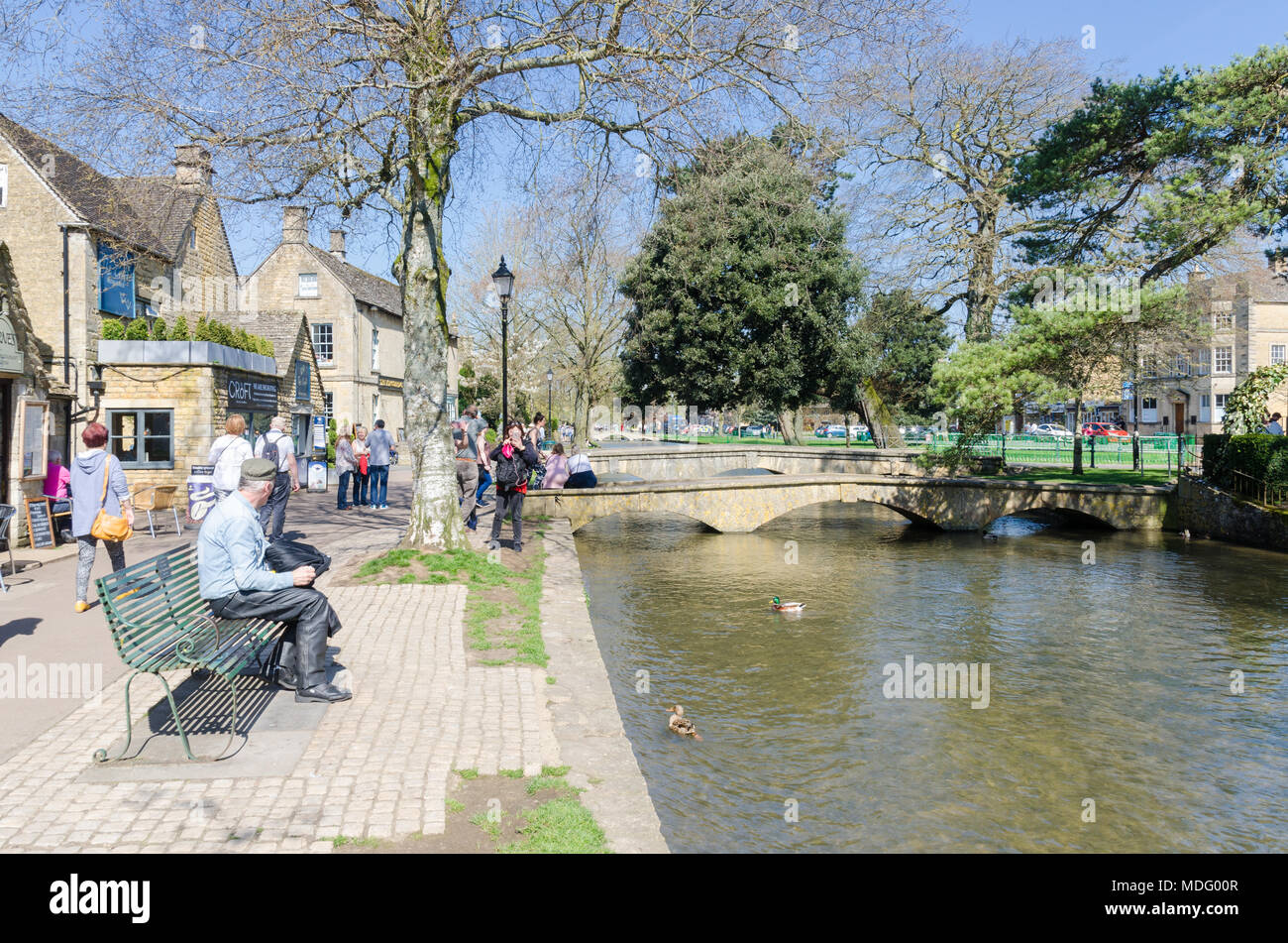 Les touristes sur la rive de la rivière Windrush dans le populaire village de Cotswold Bourton-on-the-water, Gloucestershire dans soleil du printemps Banque D'Images