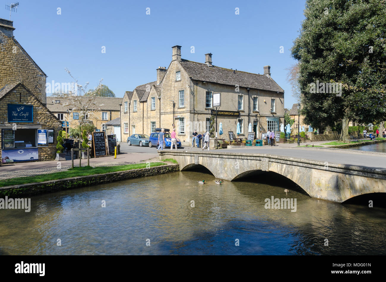 Les touristes sur la rive de la rivière Windrush dans le populaire village de Cotswold Bourton-on-the-water, Gloucestershire dans soleil du printemps Banque D'Images