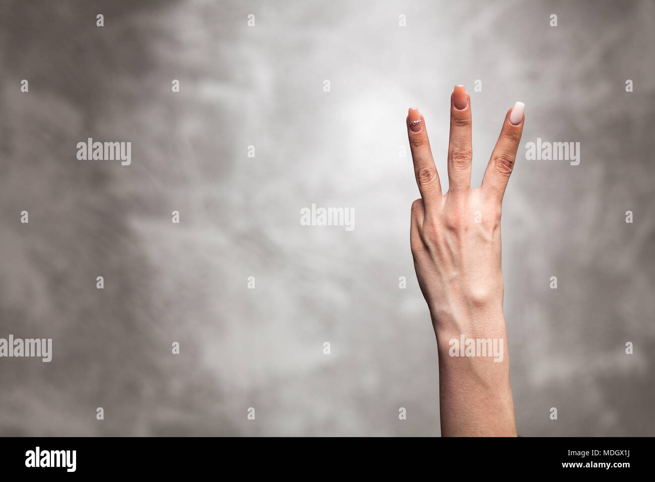 La main féminine sur fond de mur gris Banque D'Images