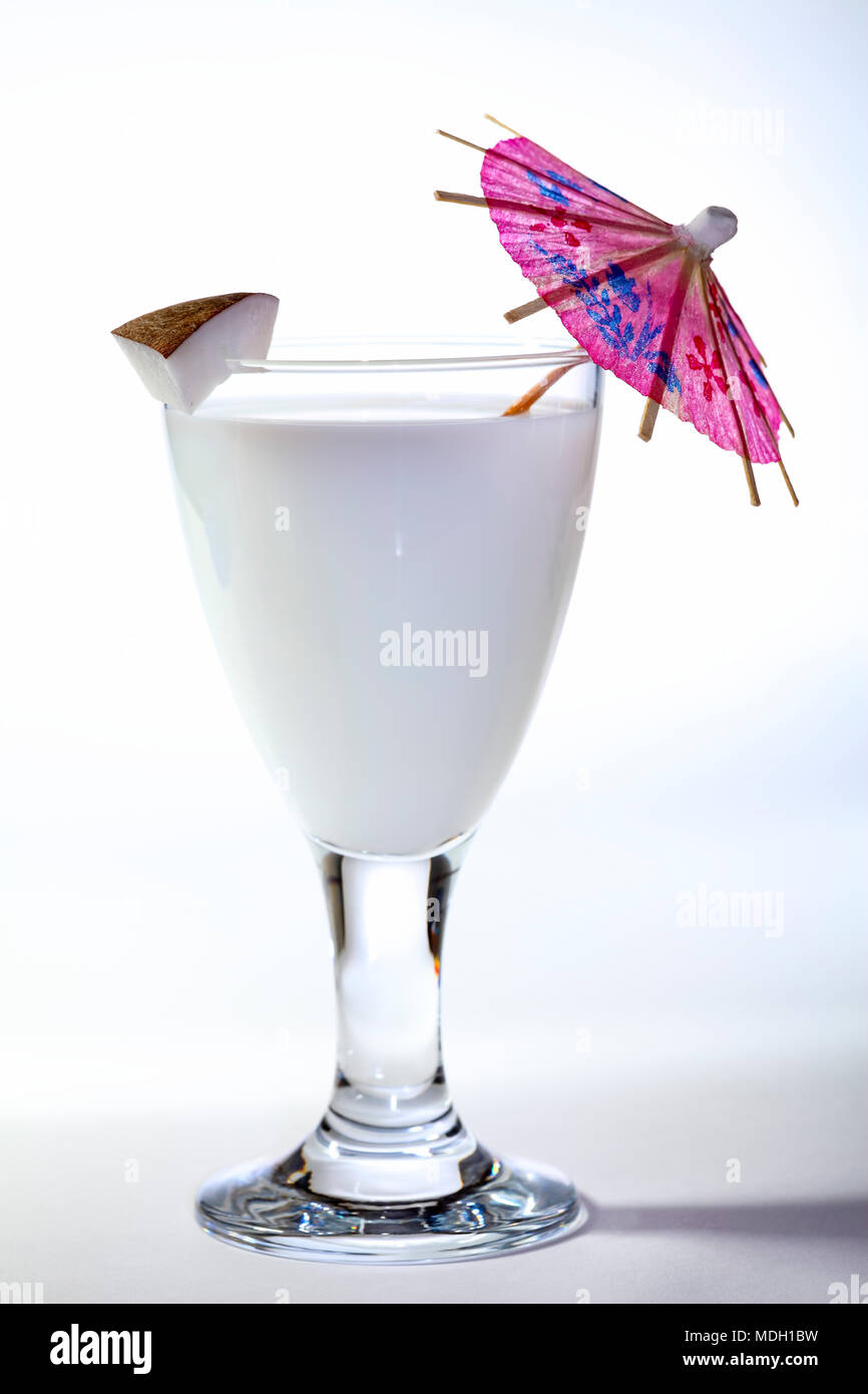 Verre de lait avec une tranche de noix de coco et un cocktail parasol isolé sur fond blanc Banque D'Images