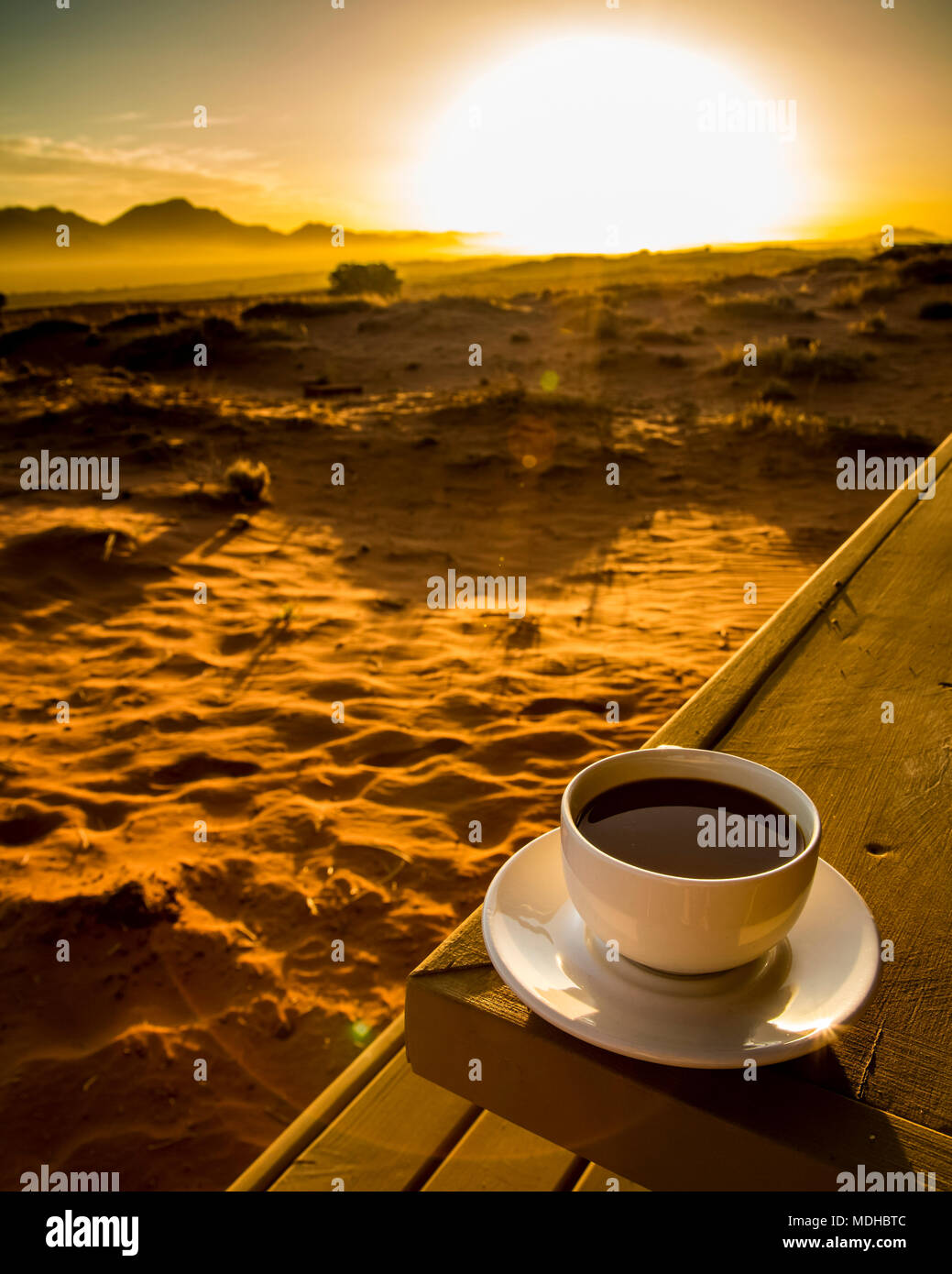 Une tasse de café se trouve sur une table en bois avec une vue sur le lever du soleil sur le désert, Sossusvlei, Namibie, région Hardap Banque D'Images