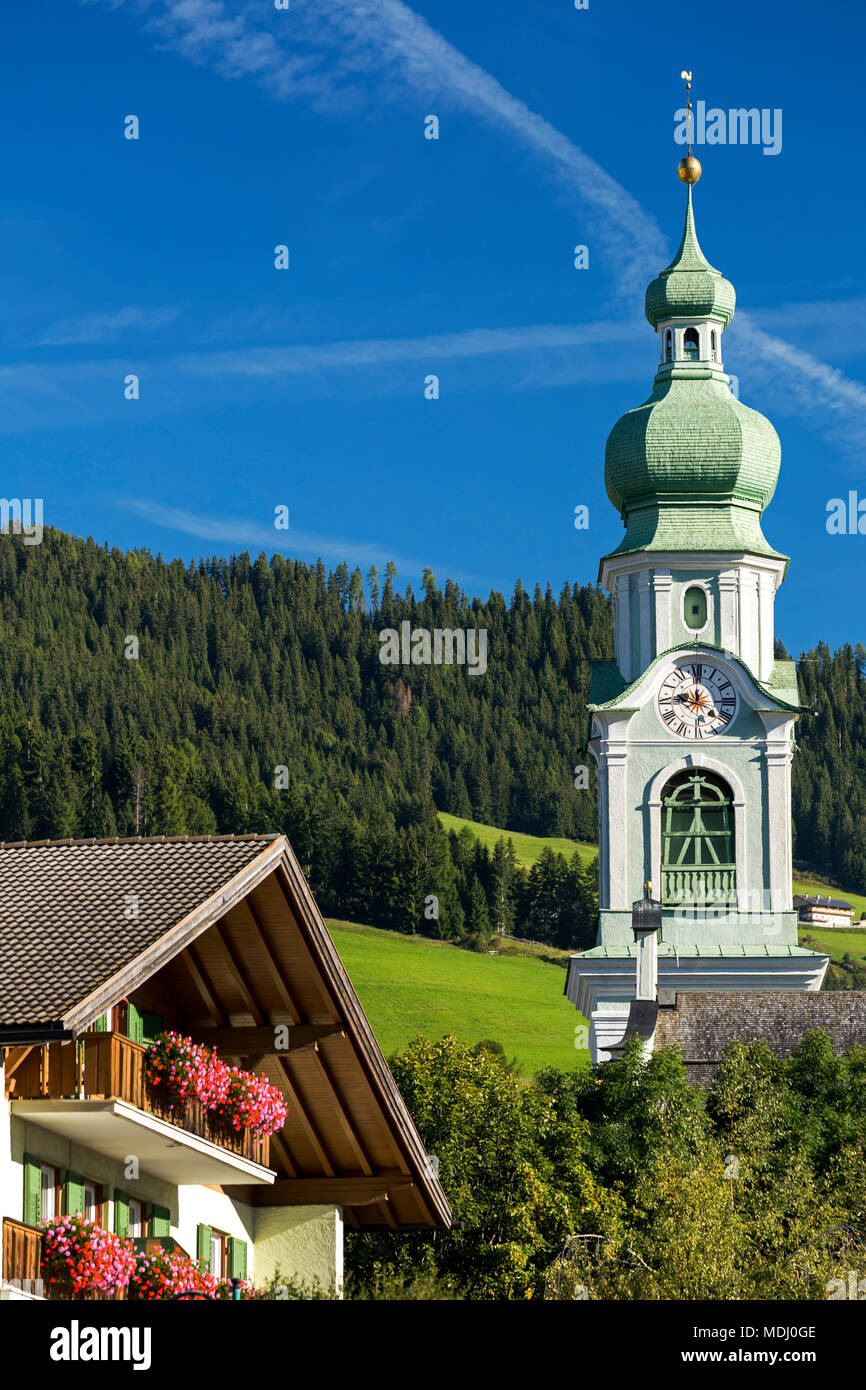 Tour de l'horloge de l'église de décoration dans le village alpin avec les boîtes à fleurs et ciel bleu ; Dobbiaco, Bolzano, Italie Banque D'Images