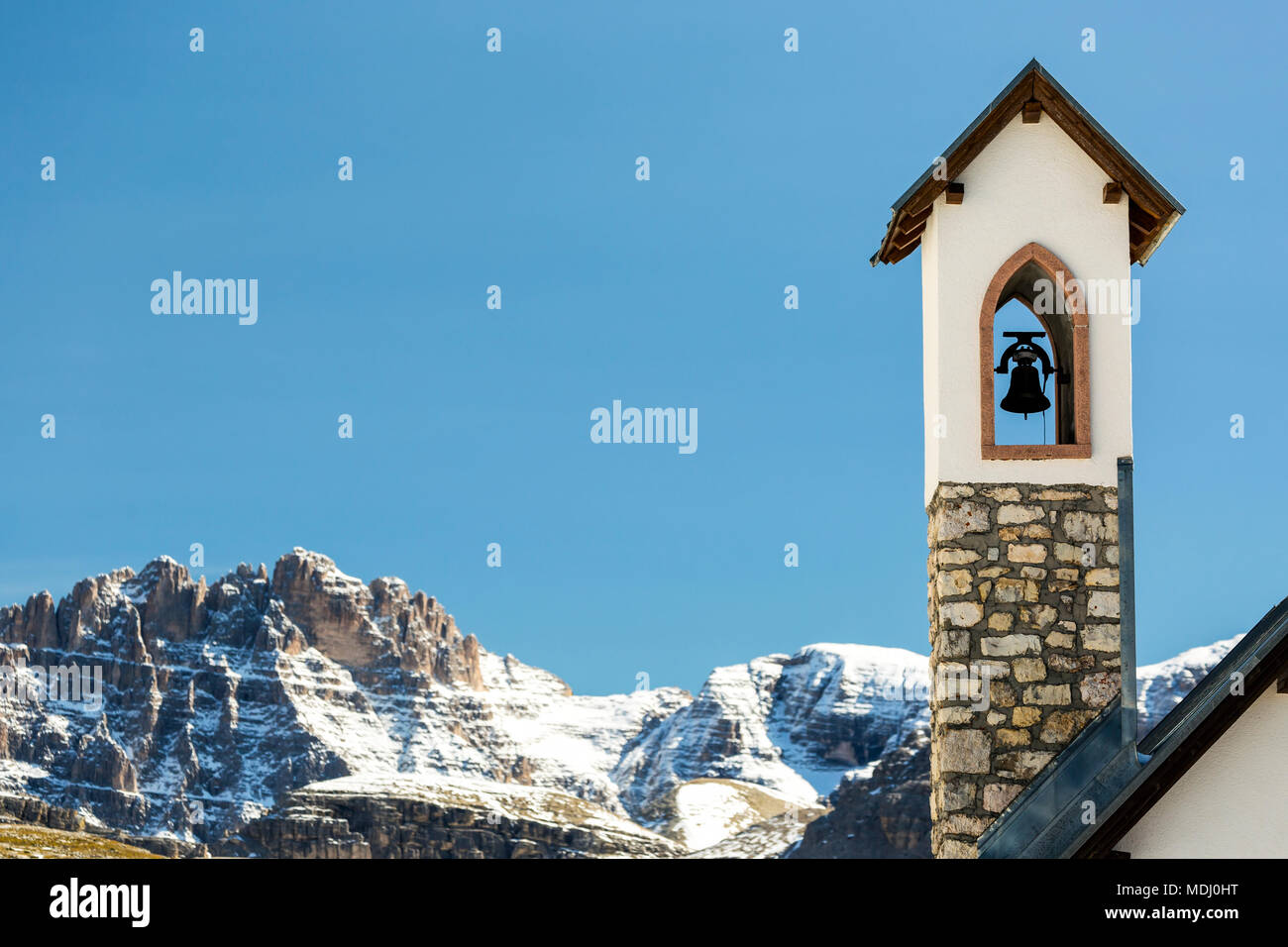 Clocher de l'église en pierre avec des montagnes couvertes de neige dans l'arrière-plan avec ciel bleu ; Sesto, Bolzano, Italie Banque D'Images