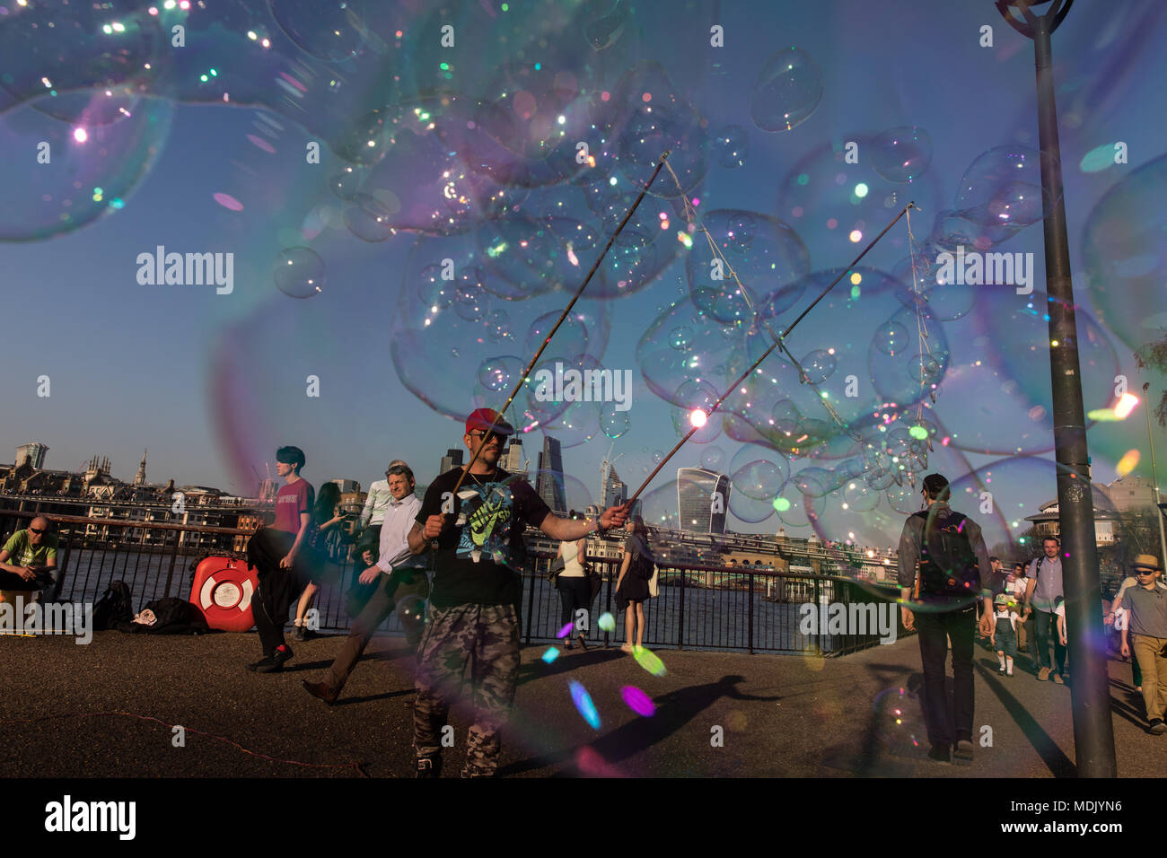 Londres, Royaume-Uni. 19 avril, 2018. Météo France : un musicien ambulant fait de bulles de passants sur la rive sud de la Tamise pendant un beau soir, à London, UK Crédit : Carol Moir Banque D'Images