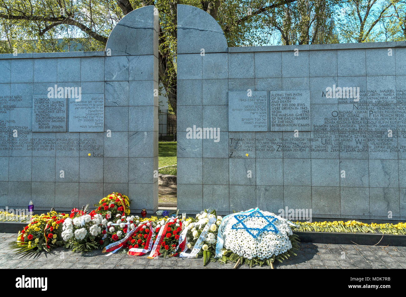 Varsovie, Pologne - 19 avril 2018 : bougie, roses et jonquilles jaunes au monument Umschlagplatz. Banque D'Images