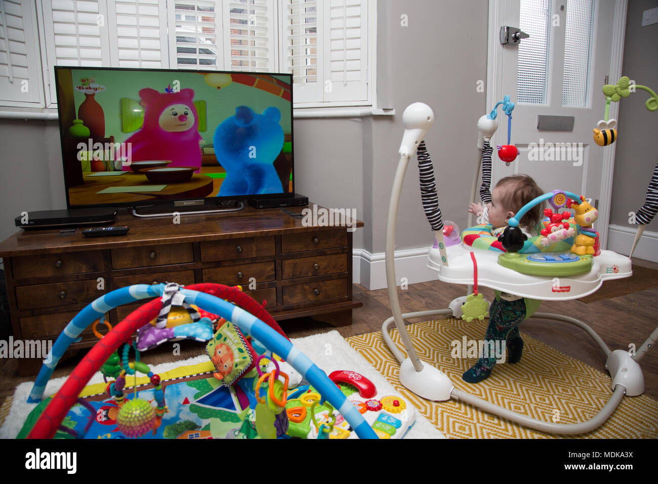 Bébé en jumperoo regarder la télévision Banque D'Images